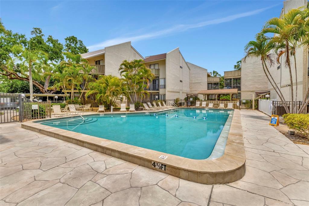 6157 Midnight Pass Road, Unit E24 Sarasota, FL 34242 - Photo 23 of 44 a view of a house with a big yard potted plants and palm trees