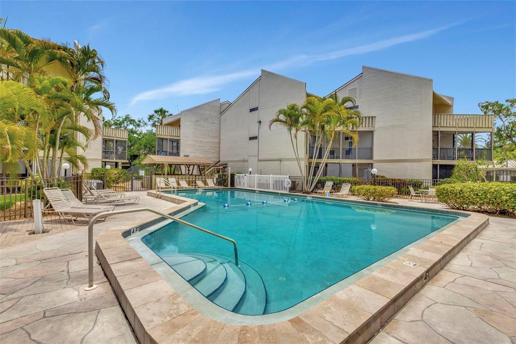 6157 Midnight Pass Road, Unit E24 Sarasota, FL 34242 - Photo 24 of 44 a view of a swimming pool with a lounge chairs