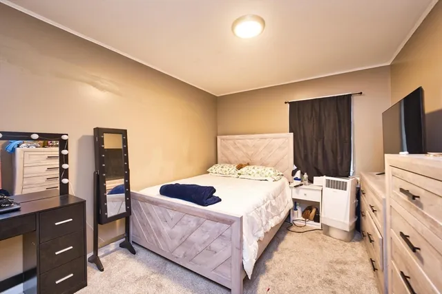 a bedroom with a bed and a flat tv screen on dresser