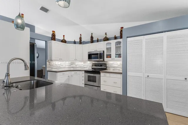 a kitchen with stainless steel appliances granite countertop a refrigerator and a stove top oven