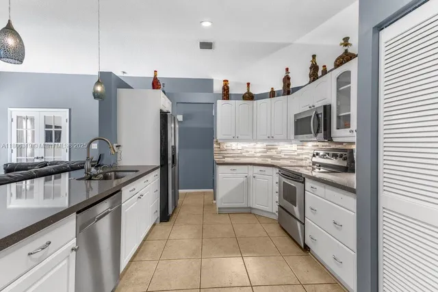 a large kitchen with stainless steel appliances granite countertop a sink stove and refrigerator