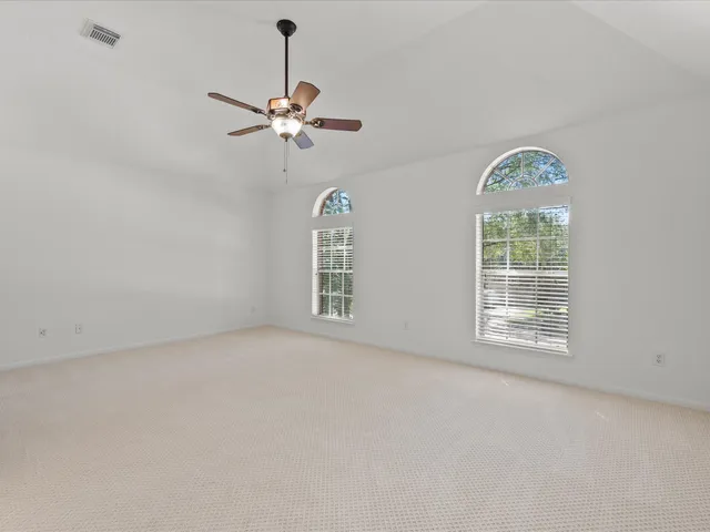 an empty room with windows and fan