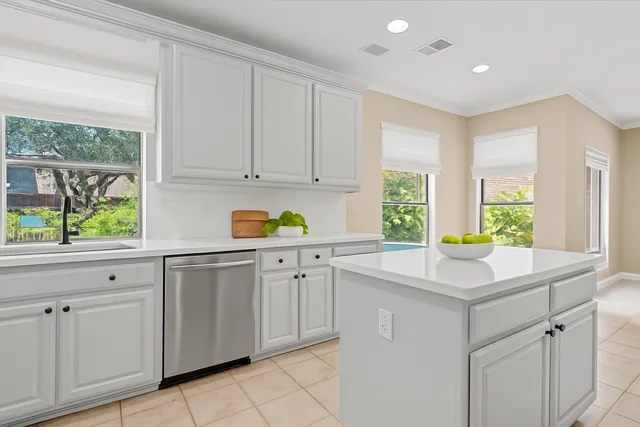 a kitchen with white cabinets and window