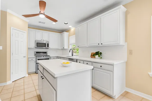 a kitchen with stainless steel appliances a stove a sink a refrigerator white cabinets and a refrigerator