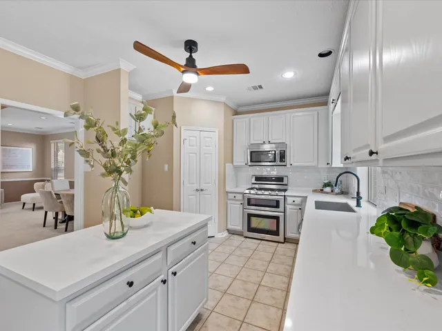 a kitchen with stainless steel appliances kitchen island granite countertop a refrigerator a stove a sink with wooden floor and cabinets