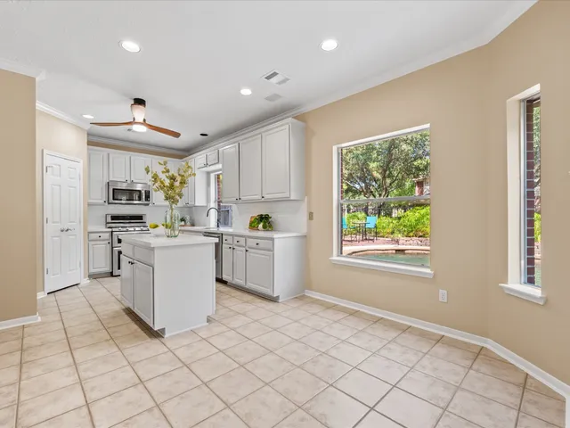 a kitchen with white cabinets and window