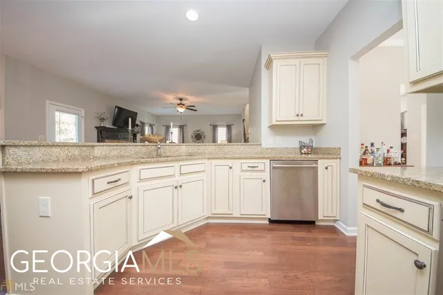 a kitchen with granite countertop a sink white cabinets and stainless steel appliances