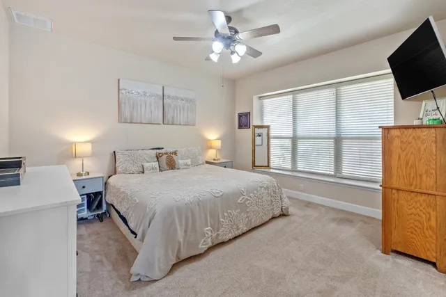 a spacious bedroom with a bed and a flat screen tv