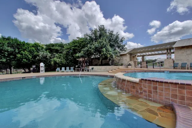 a view of swimming pool with outdoor seating and covered with trees in the background