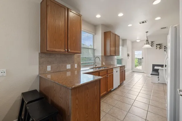a large kitchen with stainless steel appliances granite countertop a sink and a refrigerator