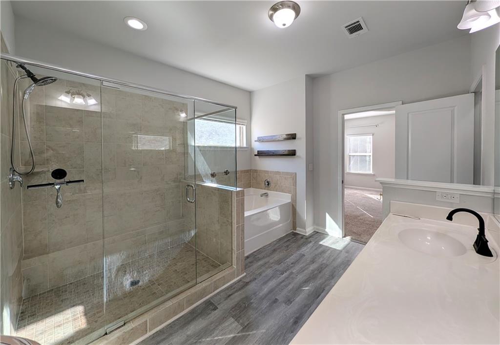 5250 Whisper Point Boulevard Cumming, GA 30028 - Photo 38 of 55 a bathroom with a sink a mirror and a glass door shower