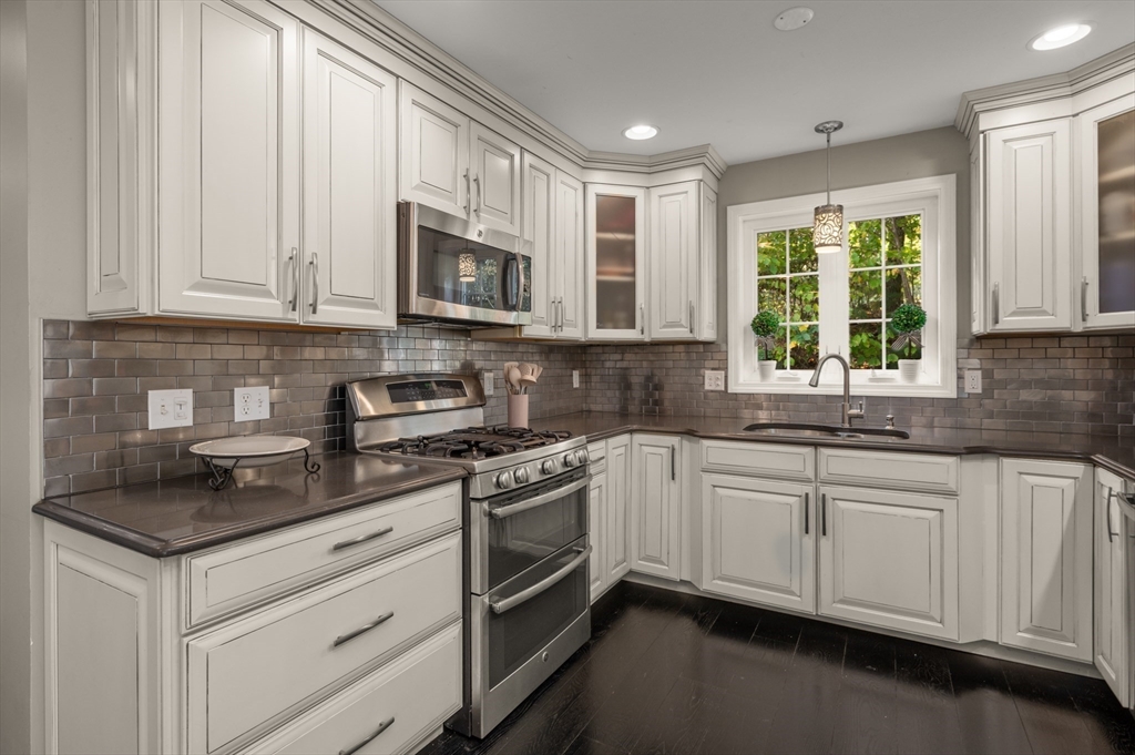 16 Autumn Woods Road Salem, NH 03079 - Photo 25 of 29 a kitchen with stainless steel appliances granite countertop white cabinets a sink a stove a window and a microwave