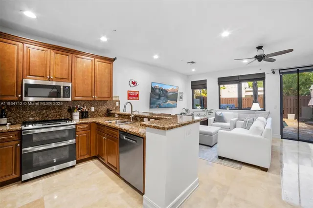 a kitchen with stainless steel appliances granite countertop a stove top oven a sink dishwasher a dining table and chairs with wooden floor