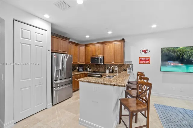 a kitchen with stainless steel appliances granite countertop a refrigerator and a stove top oven