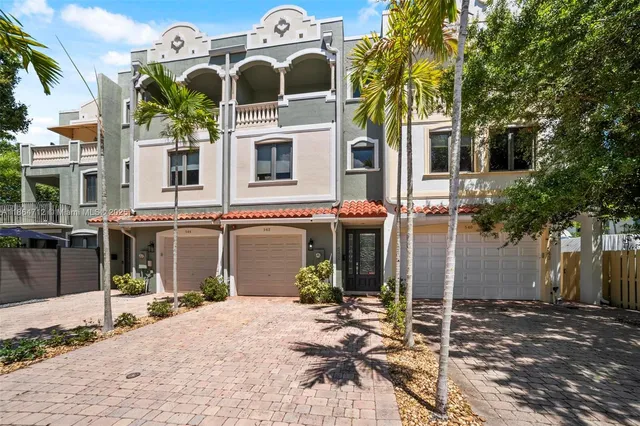 a view of a white house with large windows and a small yard
