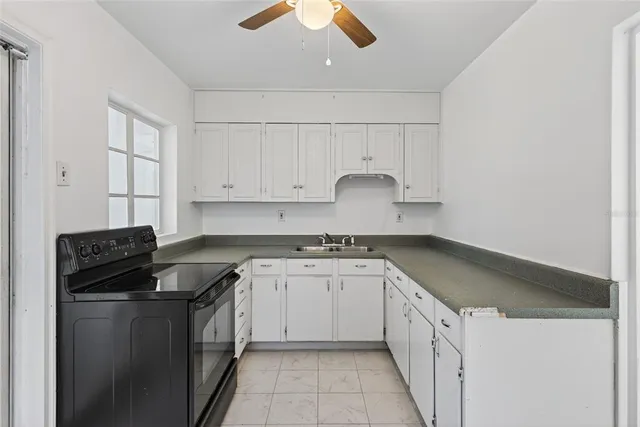 a kitchen with granite countertop a sink stove and cabinets