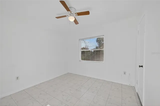 an empty room with a ceiling fan and window