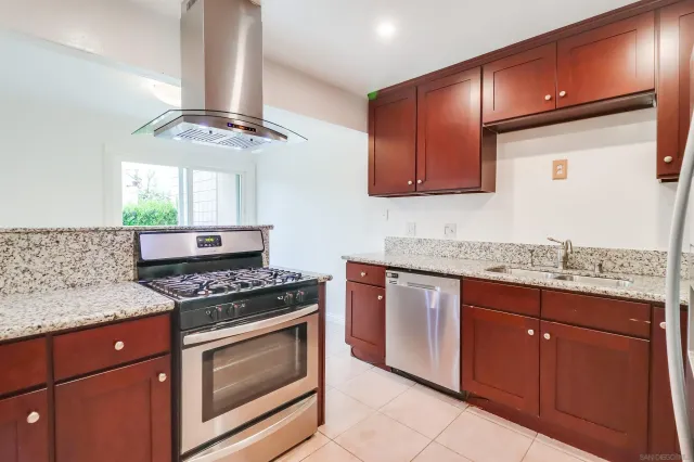 a kitchen with granite countertop stainless steel appliances a stove sink and cabinets