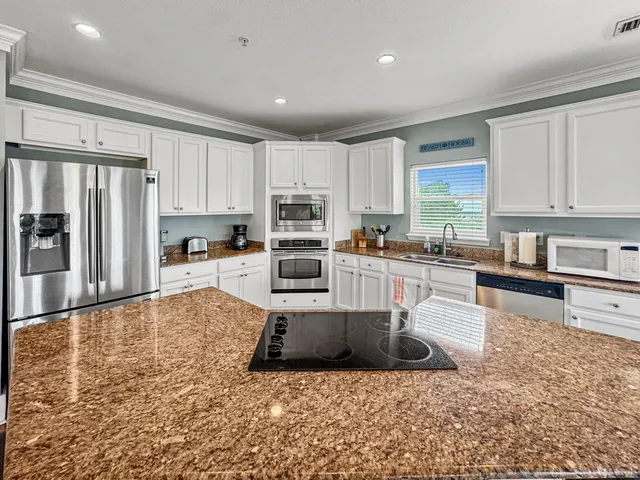 a living room with stainless steel appliances granite countertop a refrigerator sink and cabinets
