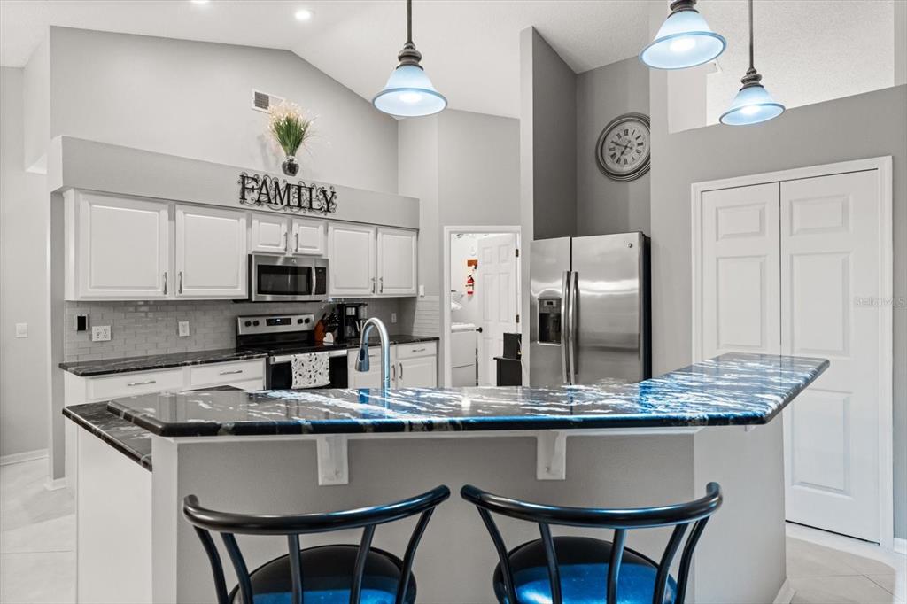 1336 Star Court Deltona, FL 32725 - Photo 11 of 34 a kitchen with granite countertop a table chairs stove and refrigerator