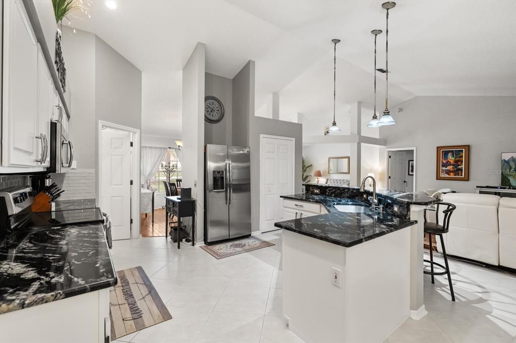 1336 Star Court Deltona, FL 32725 - Photo 10 of 34 a kitchen with stainless steel appliances granite countertop a stove a refrigerator a sink a oven a dining table and chairs with wooden floor