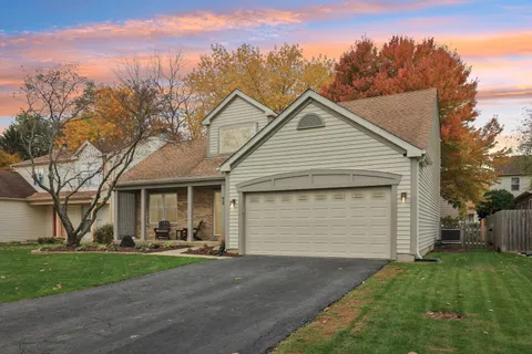 a view of a white house with a small yard and large tree