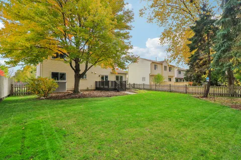 a view of a white house in front of a big yard with large trees