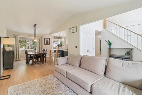 a living room with furniture and a dining table with wooden floor