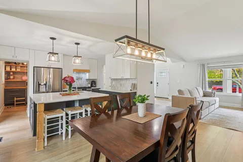 a view of a dining room and livingroom with furniture wooden floor a chandelier