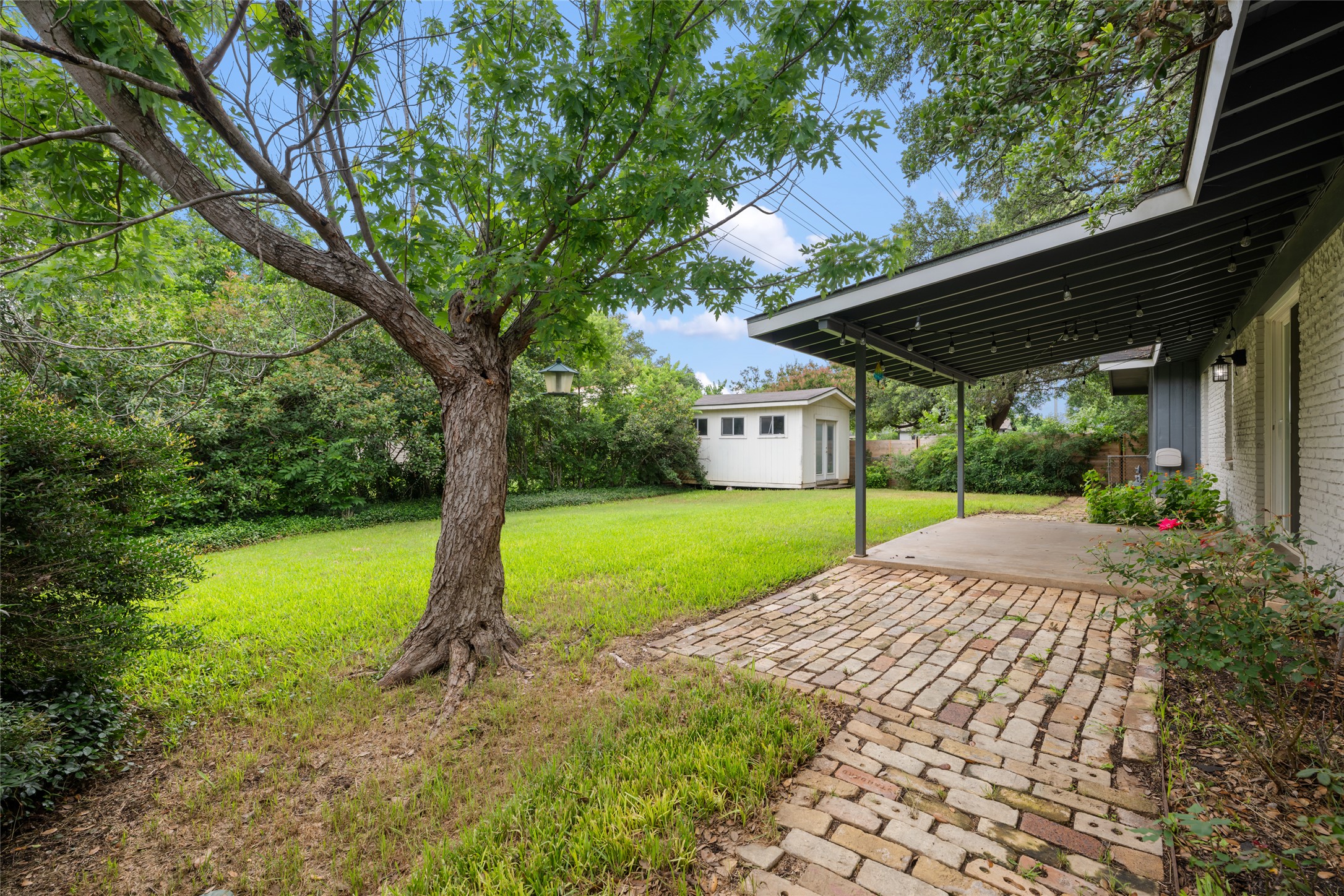 4602 Frontier Trail Austin, TX 78745 - Photo 16 of 21 A spacious yard with mature trees and a charming brick patio for outdoor enjoyment.