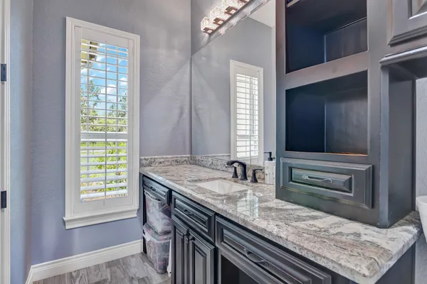 a bathroom with a granite countertop sink and a window