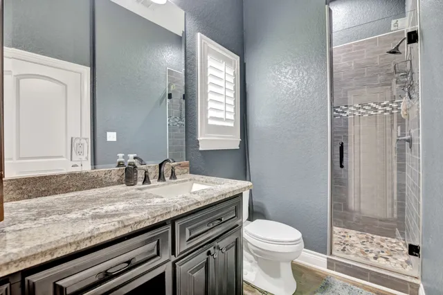 a bathroom with a granite countertop sink toilet and shower
