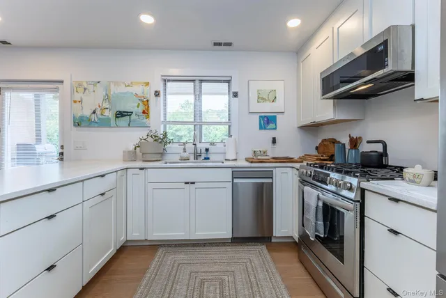 a kitchen with stainless steel appliances granite countertop a stove a sink and a microwave