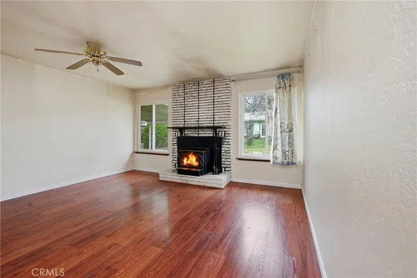 an empty room with wooden floor fireplace and windows