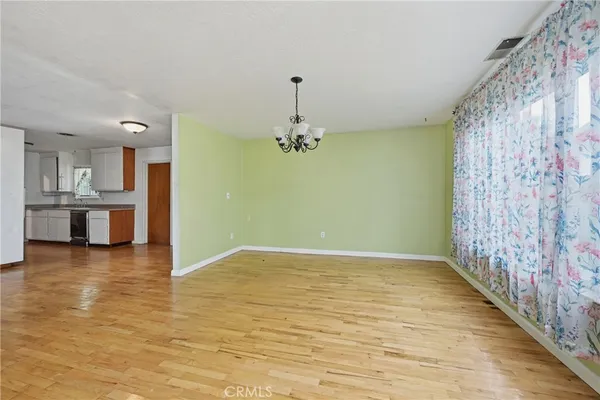 a view of empty room with wooden floor and kitchen