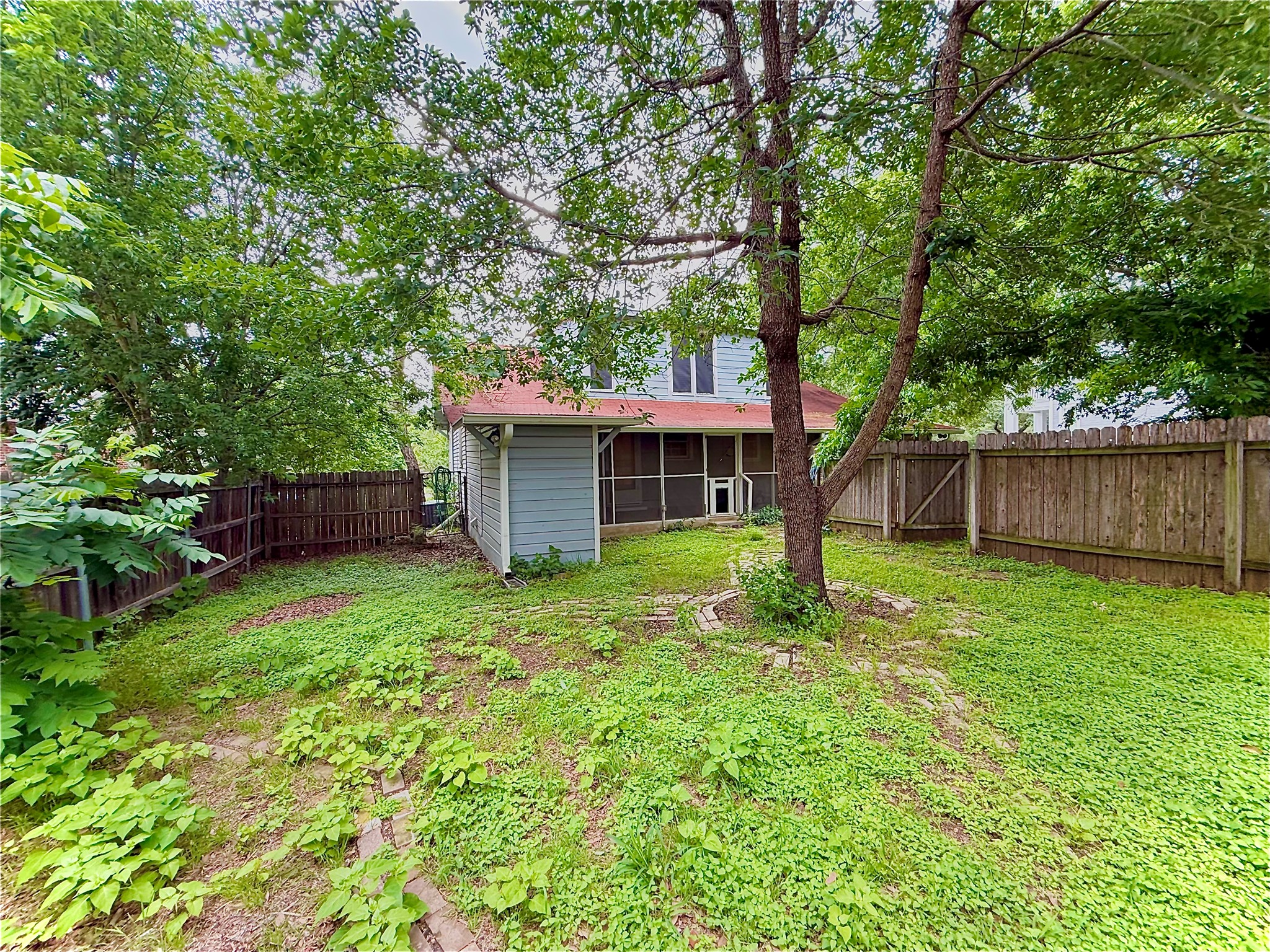423 South Main Street Lockhart, TX 78644 - Photo 24 of 26 Fenced backyard with mature trees, offering a screened porch, a side entrance, and an additional shed structure