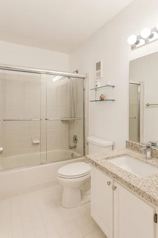 a bathroom with a granite countertop sink a toilet and shower