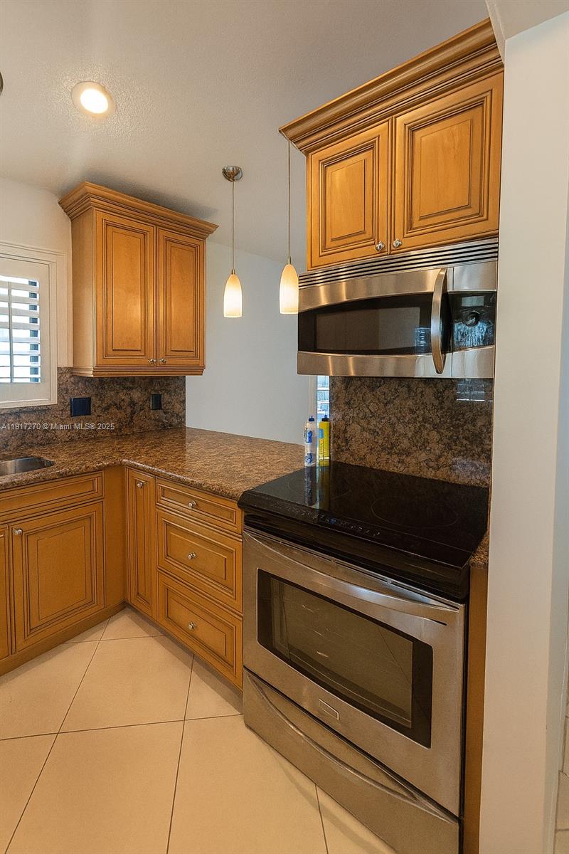 8190 Springtree Road, Unit 8190 Boca Raton, FL 33496 - Photo 3 of 23 a kitchen with granite countertop a stove sink and cabinets