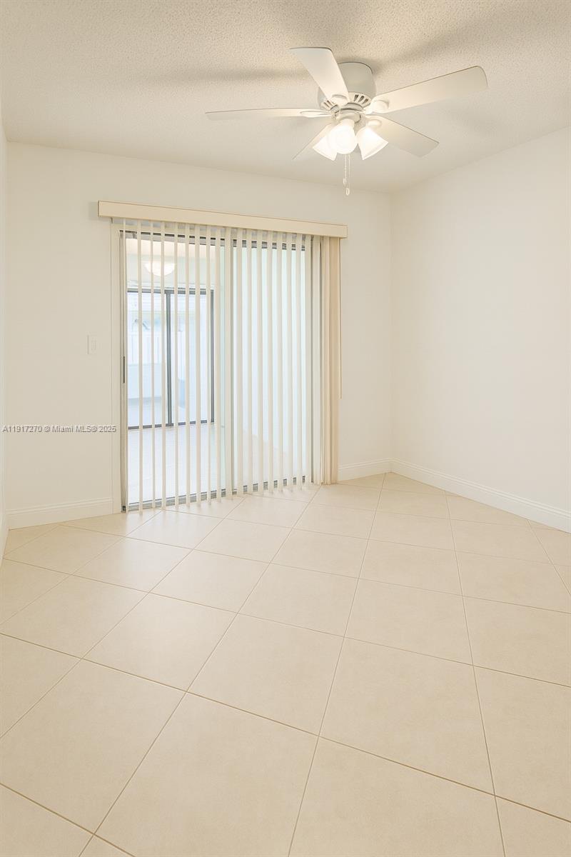 8190 Springtree Road, Unit 8190 Boca Raton, FL 33496 - Photo 10 of 23 an empty room with chandelier fan and windows