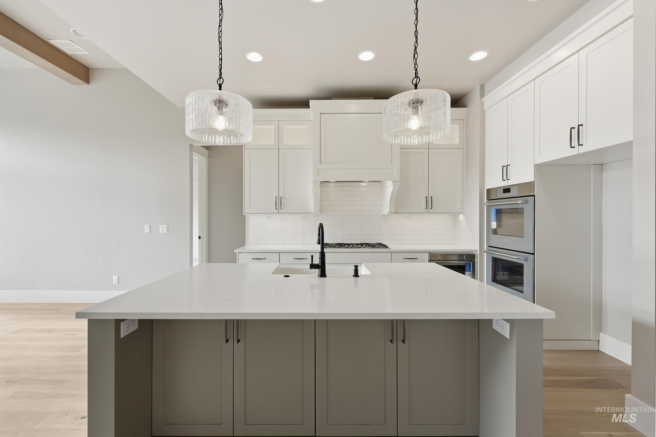 1035 East Crescendo Street Meridian, ID 83642 - Photo 12 of 50 Kitchen with white cabinets, decorative light fixtures, backsplash, double oven, and light wood-style flooring
