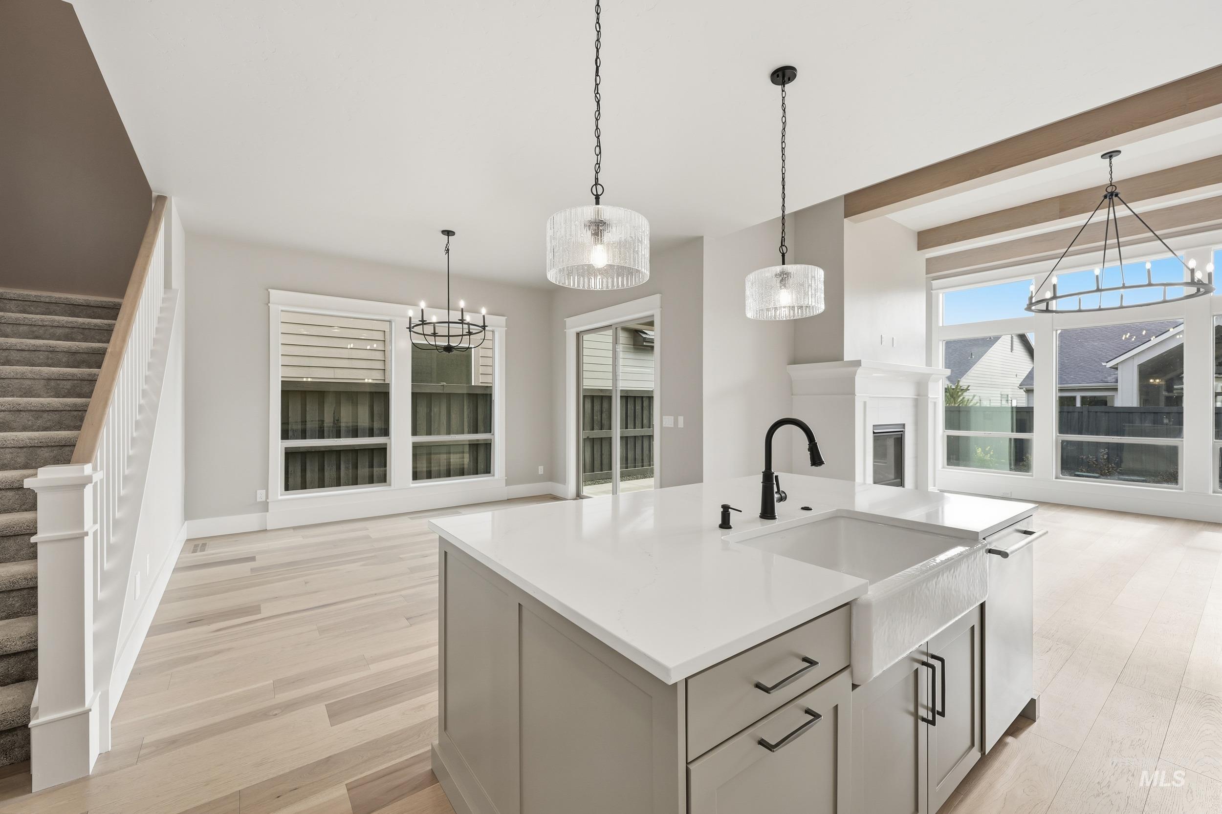 1035 East Crescendo Street Meridian, ID 83642 - Photo 14 of 50 Kitchen featuring a chandelier, light wood-style flooring, a center island with sink, decorative light fixtures, and light stone countertops