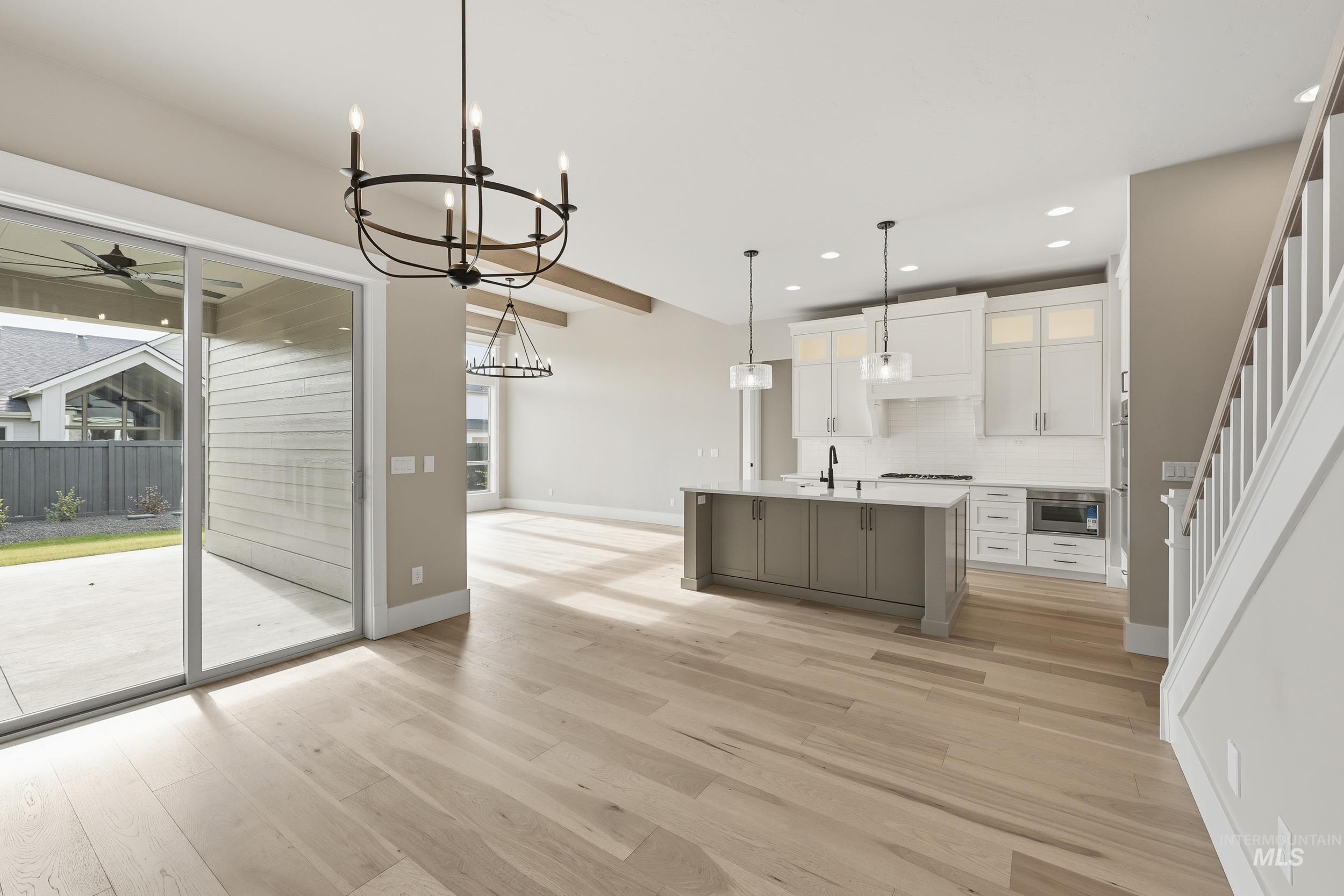 1035 East Crescendo Street Meridian, ID 83642 - Photo 15 of 50 Kitchen featuring white cabinetry, an island with sink, pendant lighting, light wood-type flooring, and tasteful backsplash