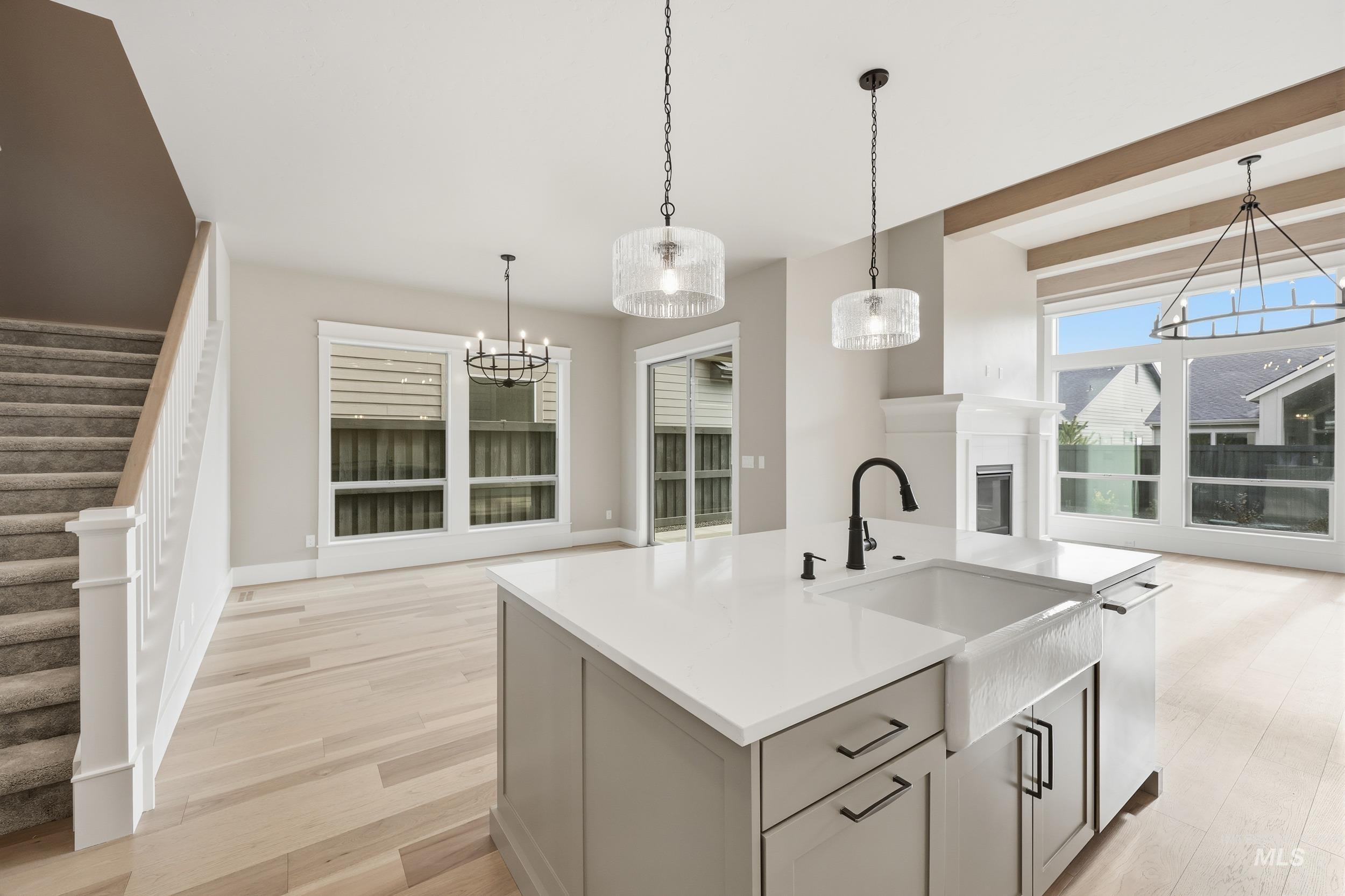 1035 East Crescendo Street Meridian, ID 83642 - Photo 16 of 50 Kitchen featuring light wood-style flooring, a chandelier, pendant lighting, a kitchen island with sink, and light stone countertops