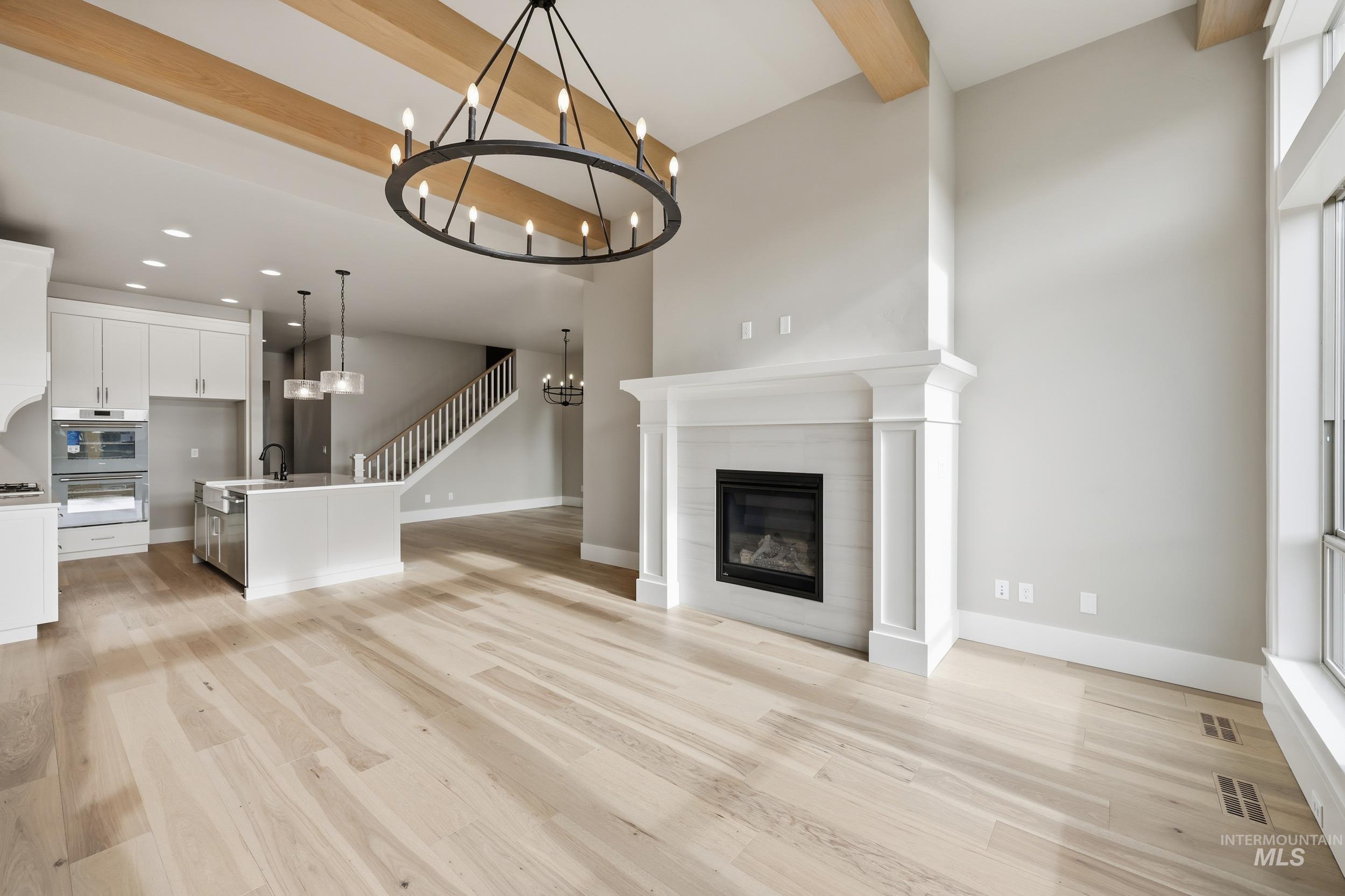 1035 East Crescendo Street Meridian, ID 83642 - Photo 4 of 50 Unfurnished living room with beamed ceiling, a tile fireplace, light wood finished floors, a chandelier, and recessed lighting
