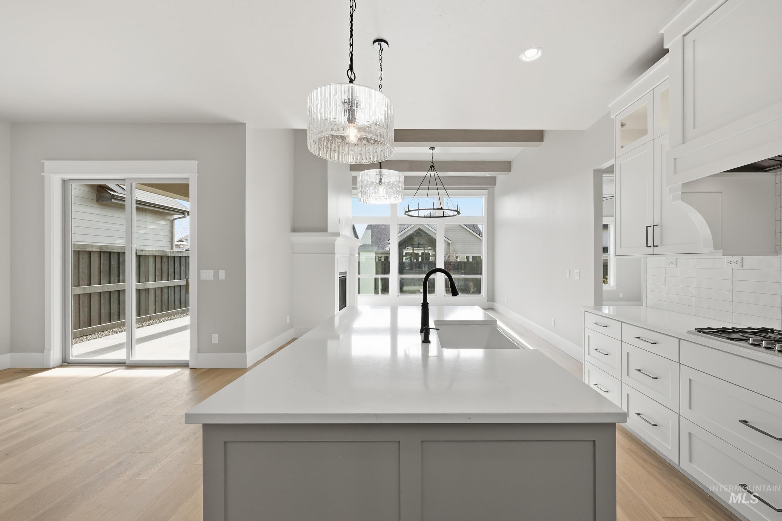 1035 East Crescendo Street Meridian, ID 83642 - Photo 7 of 50 Kitchen with backsplash, a center island with sink, decorative light fixtures, white cabinets, and light stone countertops