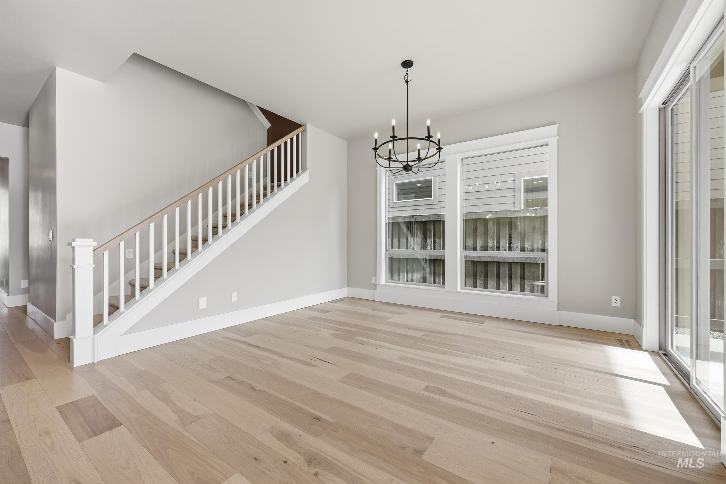 1035 East Crescendo Street Meridian, ID 83642 - Photo 8 of 50 Unfurnished dining area featuring stairway, light wood-type flooring, and a chandelier