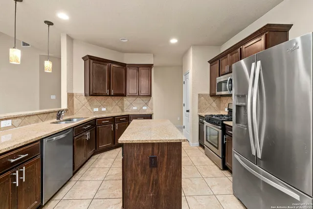 a large kitchen with stainless steel appliances granite countertop a refrigerator and a sink