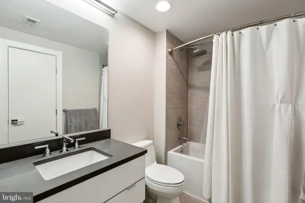 a bathroom with a granite countertop sink toilet and shower