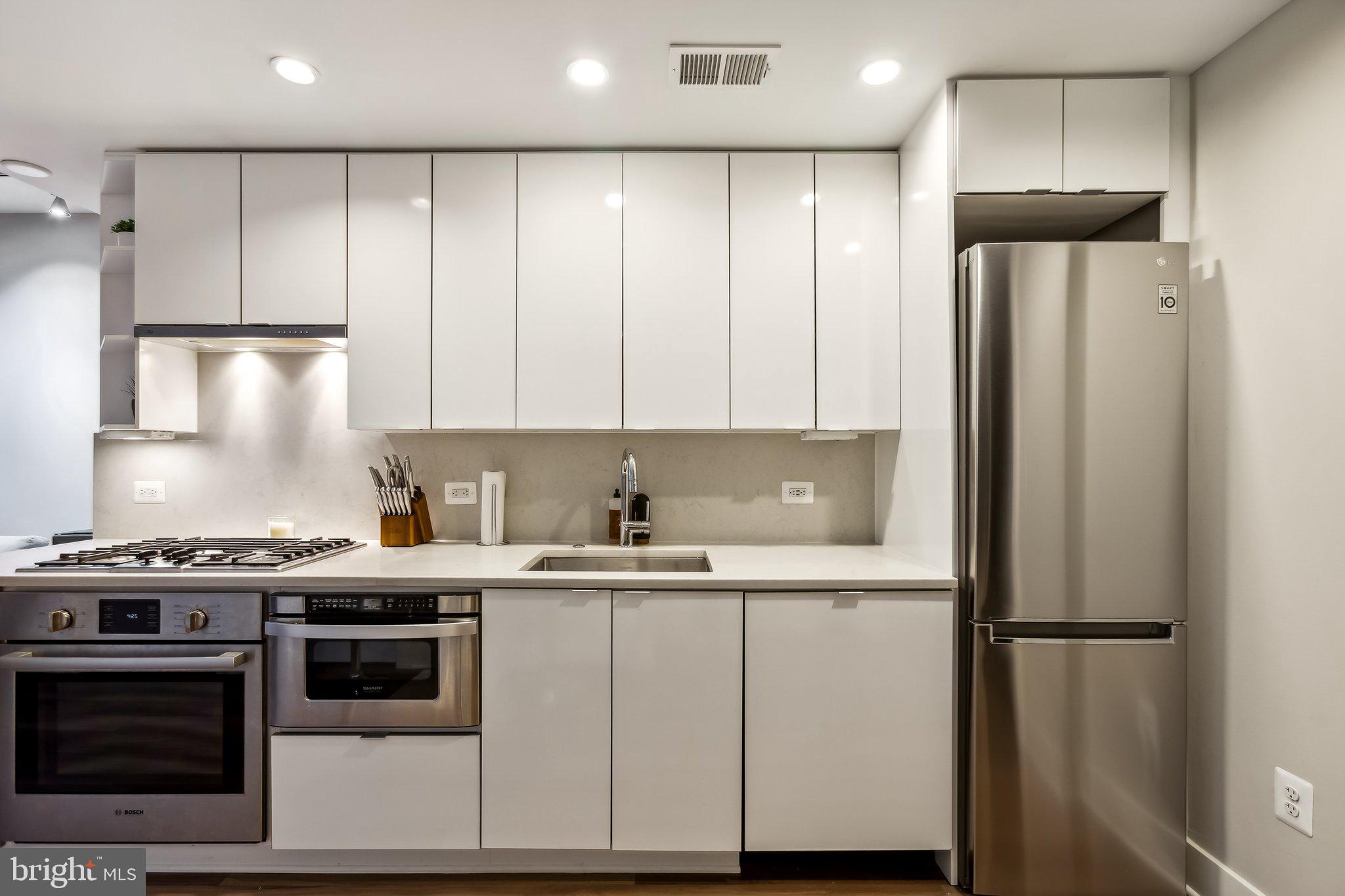1311 13th Street Northwest, Unit T04 Washington, DC 20005 - Photo 7 of 18 a kitchen with a sink a refrigerator and cabinets