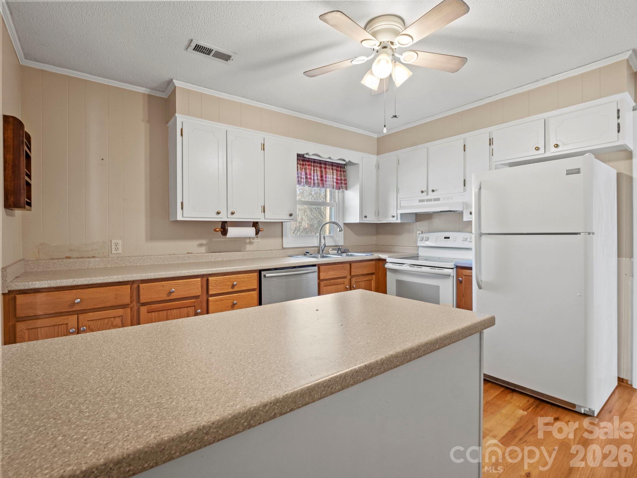 1429 Doggett Road Forest City, NC 28043 - Photo 11 of 33 a kitchen with stainless steel appliances granite countertop a refrigerator a sink dishwasher a stove with chairs and white countertops with wooden floor